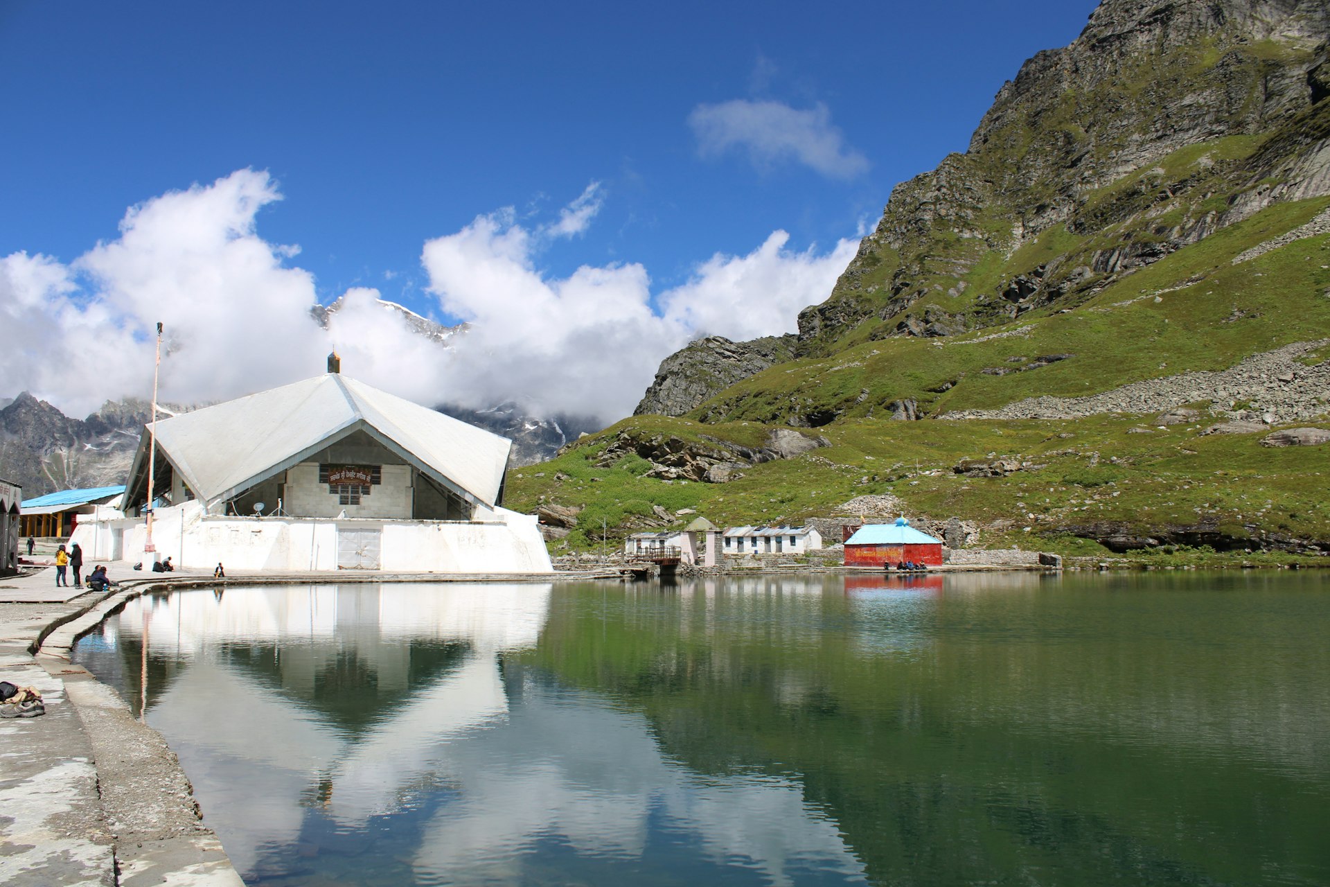 white and brown house near body of water and green mountain under blue sky during daytime